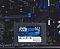 Фото-4 SSD Patriot P220 512GB, накопитель на фоне материнской платы; чёрный 2.5-дюймовый корпус с синей наклейкой расположен перед платой с тёмными компонентами и синими слотами. Фото показывает продукт в рабочем контексте для страницы товара.
