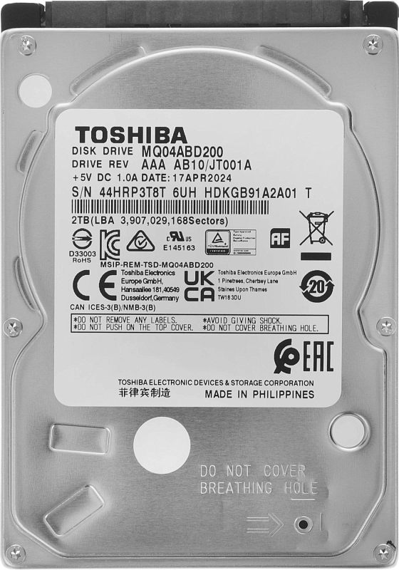 Фото-1 Жесткий диск Toshiba MQ04ABD200 2 ТБ, вид сверху на крышку; видна белая сервисная этикетка, штампованная металлическая крышка и компактный корпус 2.5 дюйма. Серебристый, белый и черный цвет. Изображение для карточки товара, чтобы показать модель и верхнюю часть диска.