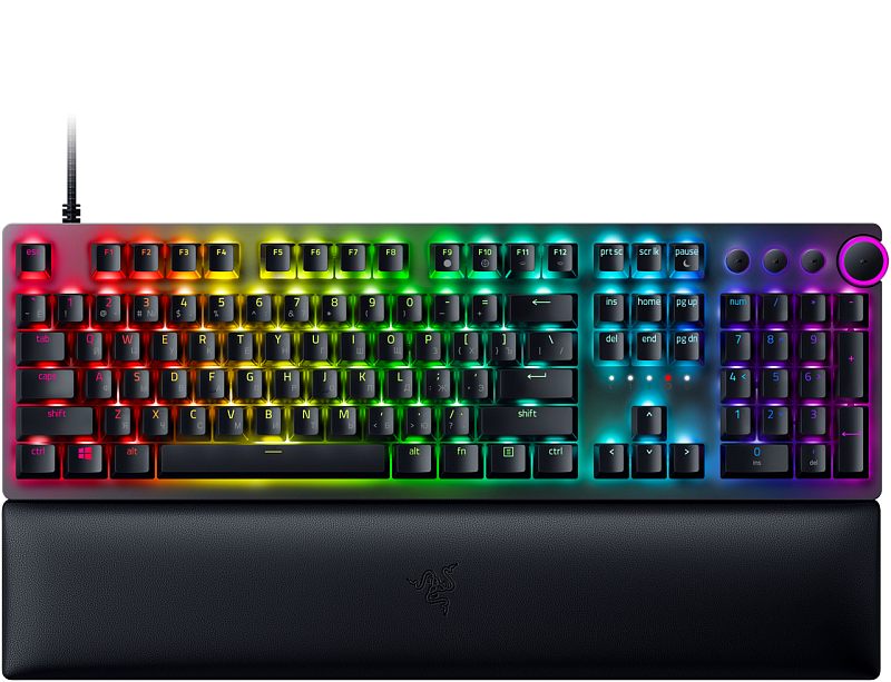 Фото-1 Клавиатура Razer Huntsman V2, вид спереди с подставкой для запястий; полноразмерная раскладка с цифровым блоком, чёрный корпус, RGB-подсветка клавиш, круглой регулятор громкости и отдельные мультимедийные кнопки справа. Для страницы товара важно, потому что изображение показывает формат клавиатуры и комплект с подставкой.
