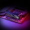 Фото-9 Комплект памяти ADATA XPG Lancer Blade AX5U6000C3616G-DTLABBK, установленная планка на материнской плате с фиолетовой подсветкой фона. Показан радиатор с диагональным рельефом, слот памяти и часть текстолита платы. Чёрный цвет. Фото для карточки товара показывает внешний вид модуля в рабочем окружении корпуса с подсветкой.