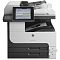 Фото-4 МФУ HP LaserJet Enterprise M725dn, фронтальный вид в процессе вывода листа; на экране отображается меню, виден выходной лоток с документом и кнопка питания на передней панели. Изображение показывает рабочий сценарий использования для страницы товара.