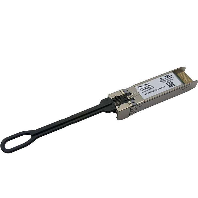Фото-1 Трансивер Brocade XBR‑000412 SFP+, вид под углом: чёрная вытяжная петля, на корпусе наклейка Brocade, заметны защёлка и направляющие, сзади частично видна контактная группа. Серебристый корпус с чёрным элементом, предметная съёмка; помогает распознать форм‑фактор SFP+ для установки в порт оборудования.