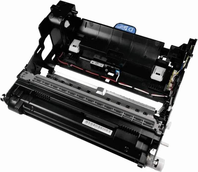 Фото-1 Барабан Kyocera DK-3130 302LV93045, вид сверху под углом на белом фоне; чёрный модуль с длинной светлой планкой, видимыми проводами внутри корпуса, боковой платой и цилиндрическим валом по нижнему краю; фото помогает оценить компоновку узла и форму корпуса на странице товара о лазерном барабане Kyocera.