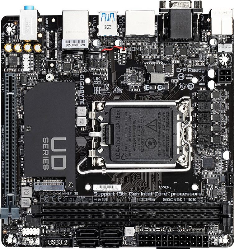 Фото-1 Материнская плата Gigabyte H610I (UD Series): вид сверху на чёрную mini‑ITX плату с сокетом LGA1700 под защитной крышкой и крупным радиатором «UD SERIES»; видны два слота DIMM, один PCIe x16 и два порта SATA у нижнего края. На белом фоне; важно для оценки форм‑фактора и компоновки.