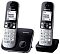 Фото-2 DECT‑телефон Panasonic KX‑TG6812RU: две трубки и основания, ракурс 3/4; чёрно‑белые трубки с белым экраном, слева база с круглой кнопкой, справа зарядная подставка; на белом фоне — важно для понимания состава комплекта и внешнего вида под углом.
