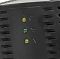 Фото-5 Стабилизатор напряжения Powercom TCA-1200 Black, крупный план передней панели с тремя индикаторами и рельефными значками, чёрный корпус с вентиляционными прорезями, на белом фоне &mdash; для понимания индикации на странице товара.